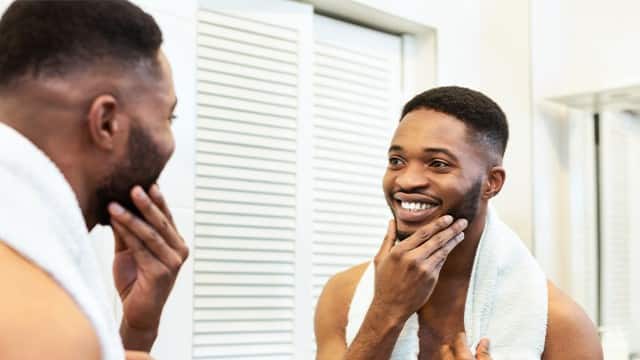 Muž se na sebe dívá do zrcadla a usmívá se přitom